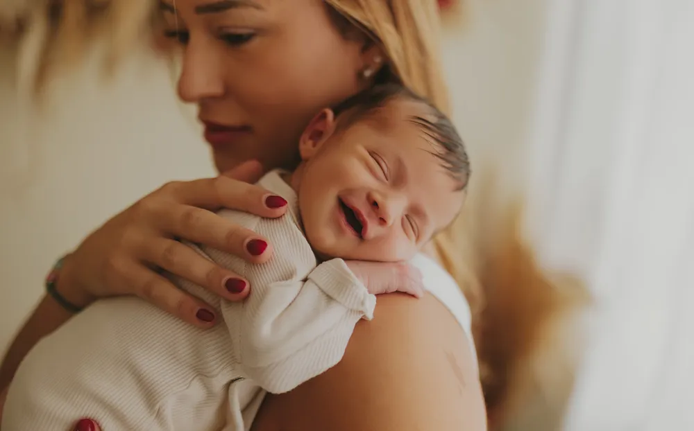 foto de recién nacido en brazos de mamá riendo